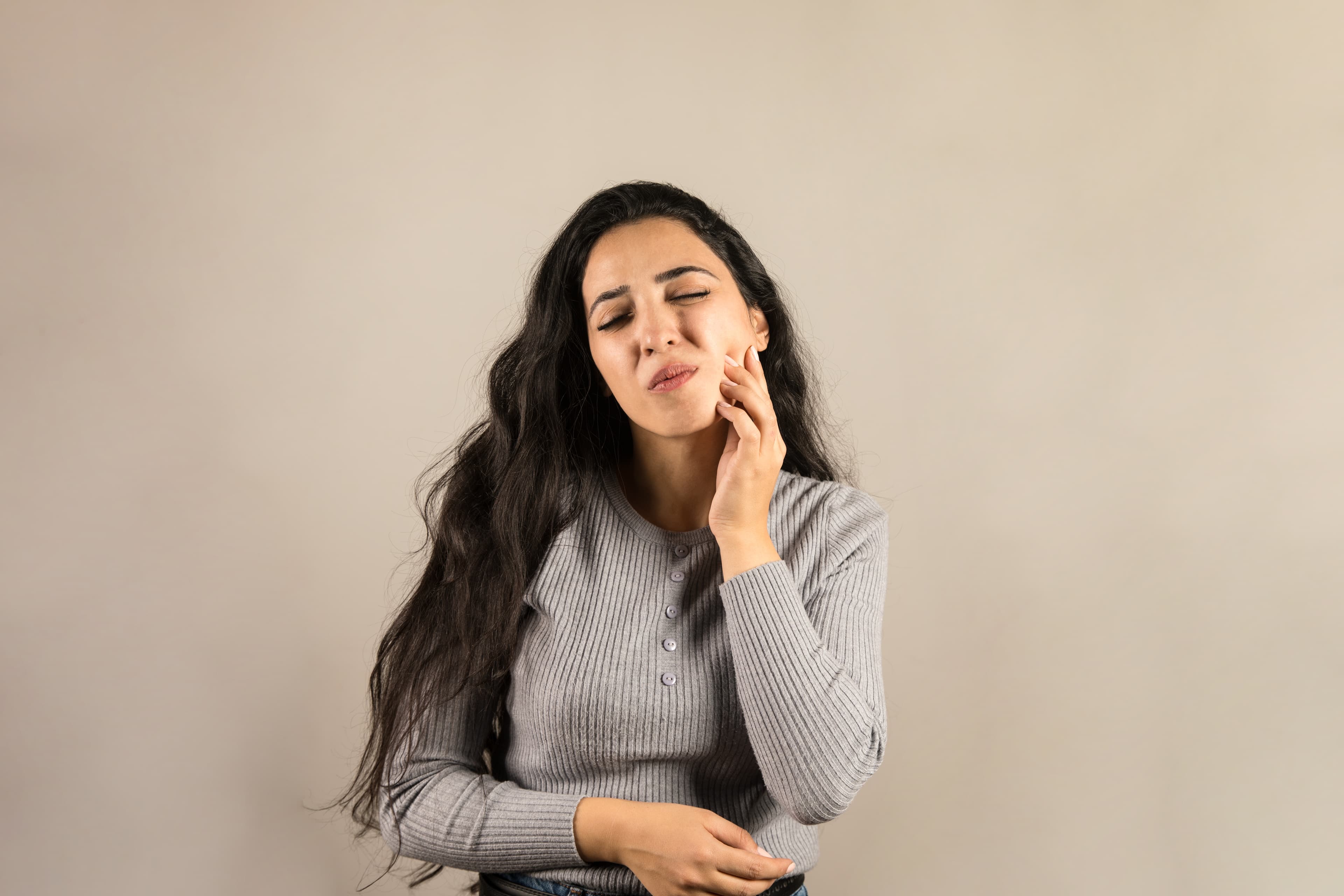 Young woman holding cheek in pain from severe toothache